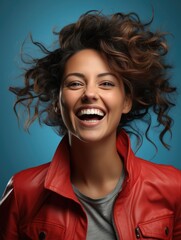 A joyful woman with dynamic hair poses in a red leather jacket
