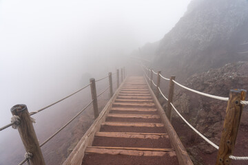 wooden stairs on a foggy day on the pedestrian path to the top of the mount vesuvio volcano....