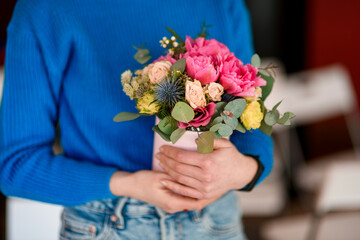 Female hands of a florist hold a delicate bouquet of pink peonies, roses and wildflowers