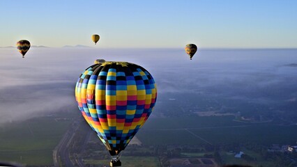 several multicolored hot air balloons are flying above the earth