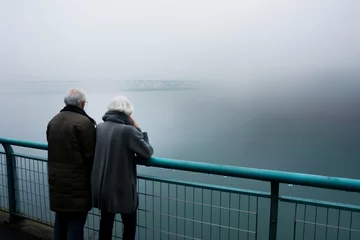 Deurstickers senior couple admiring the view from a foggy bridge viewpoint © studioworkstock