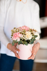 Female hands of a florist hold a delicate bouquet of pink and white carnations and white gypsophila
