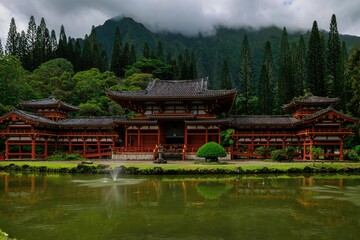 Scenic view of an Asian-style traditional building in a green forest with a pond