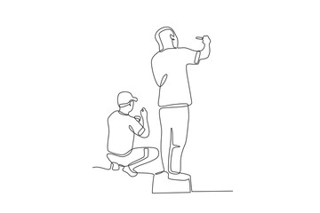 Two artists painting city walls sitting and standing