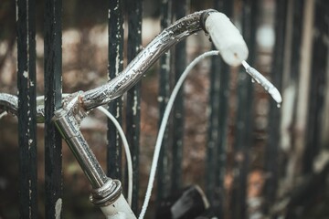 Vintage-style bicycle propped up against a metal railing, with a backdrop of rusted iron bars