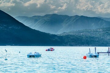 Small sailboats moored in a serene Iseo lake in Italy, with mountains in the background