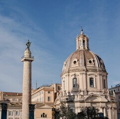 Fototapeta na wymiar Aged Basilica Ulpia with a number of ornate sculptures against a blue sky
