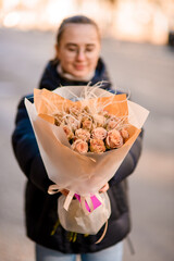 Close up of a bouquet of yellow roses in yellow and frosted wrapping paper held by a young woman