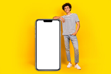 Full body cadre of young satisfied promoter guy xiaomi gadget update for users near board display phone isolated on yellow color background - obrazy, fototapety, plakaty