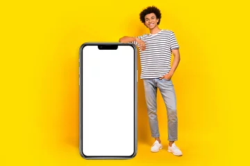 Foto auf Acrylglas Antireflex Full body cadre of young satisfied promoter guy xiaomi gadget update for users near board display phone isolated on yellow color background © deagreez