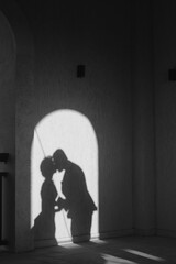 A vertical shot of kissing married couple's shadow dropping on the wall