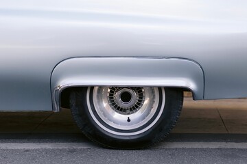 Closeup of the front wheel rim on a silver vintage car