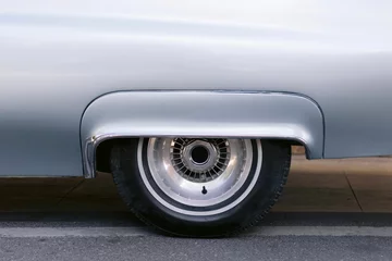 Foto auf Acrylglas Closeup of the front wheel rim on a silver vintage car © Wirestock