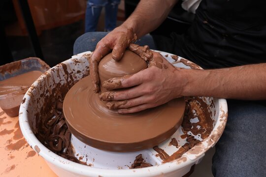 Person working on pottery in a clay bowl