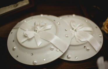 Set of two white plates with decorative bows set up on a wooden table surface.