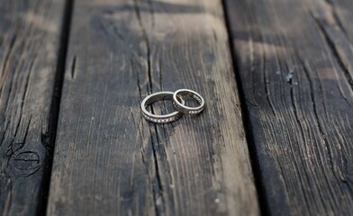 Two wedding rings placed on a wooden surface, illuminated by a natural light.
