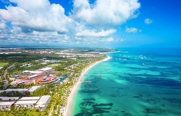 High aerial view of the Punta Cana coast with many all inclusive hotels. Large white sand beach and turquoise water of the Caribbean sea. Best summer vacations for family and honeymoon 