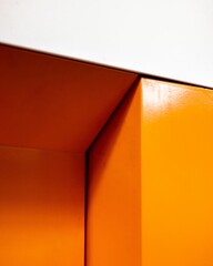 Minimalist interior design featuring an angled corner between two sections of a bright orange wall