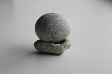 Perfect oval granite stone balances on stone stand isolated on white