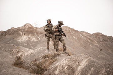 Soldiers in camouflage uniforms aiming with their rifles.ready to fire during military operation in...