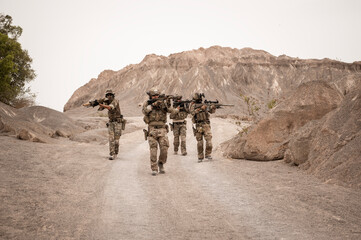 Soldiers in camouflage uniforms aiming with their rifles.ready to fire during military operation in...