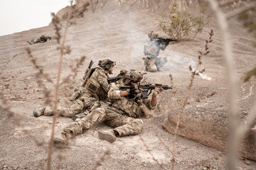 Soldiers in camouflage uniforms aiming with their rifles.ready to fire during military operation in...