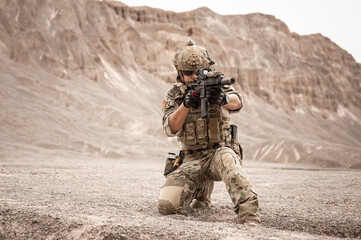 Soldiers in camouflage uniforms aiming with their rifles.ready to fire during military operation in...