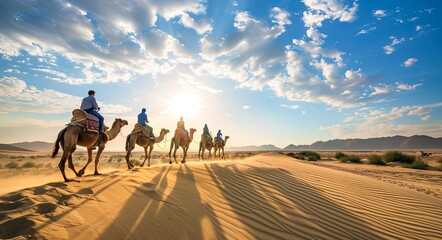 The group of people riding camels in the desert dunes, backlighting