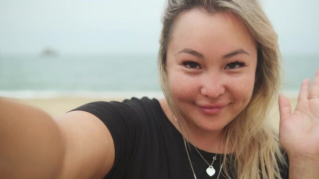 Young asian pretty woman making selfie with happy smile with ocean beach on background
