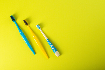 Three toothbrushes yellow and blue on a yellow background. Family dental hygiene in dentistry. Copy...