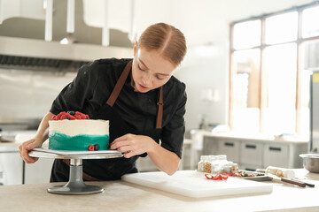Medium shot view of a bright production in a confectionery shop. A young red haired charming woman...