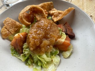 roast pork belly with apple sauce crackling and hispi cabbage on white plate on wood table