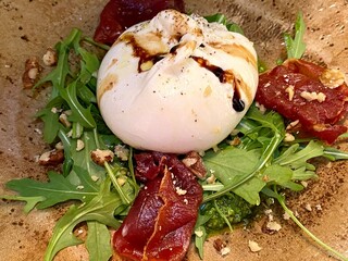 burrata Italian cows milk cheese salad with crispy fried parma ham crushed walnuts and dressed with olive oil and balsamic (Burrata is combine mozzarella and cream)