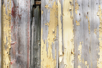 Close-up of aged wooden planks with flaking yellow paint, revealing layers of history.