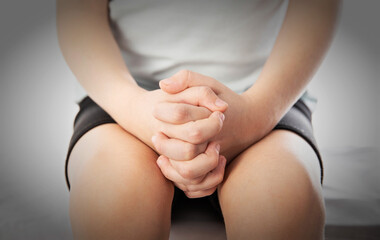 The girl's hands are folded on her knees, close-up. Bullying concept at school, emotional