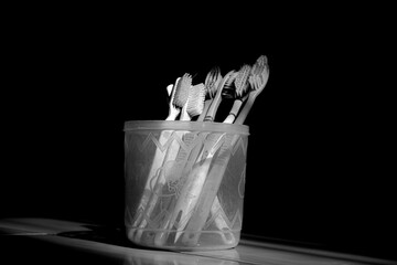 group of toothbrushes in plastic jar isolated black background