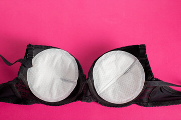 Black bra with liners for the female breast against the flow of milk on a pink background. Womens...