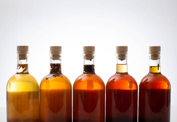 Transparent bottles with brown alcoholic drink on a white background. The concept of homemade...