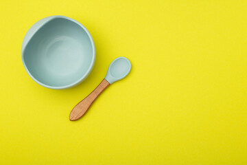 Blue children's plate and spoon on a yellow background. The concept of proper complementary feeding of children with gluten-free food. Copy space for text, vegetable protein