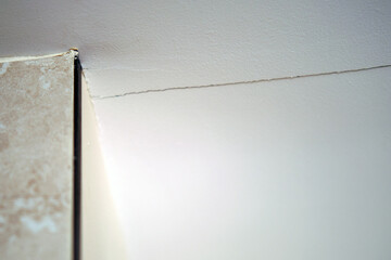 Cracked walls inside a house in an apartment, white wall with a crack