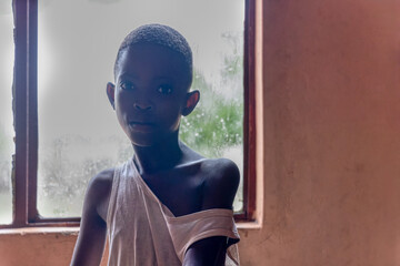 africa famine, sad and skinny girl with tiny body and skinny arms, backlight from the window in a...