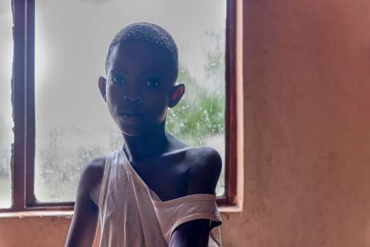 africa famine, sad and skinny girl with tiny body and skinny arms, backlight from the window in a room