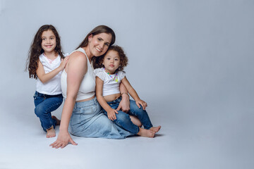 Fototapeta na wymiar young latin mother sitting posing with her two young pretty daughters
