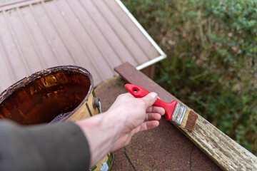 Verwittertes Holzdach mit Wetterschutzlack pinseln