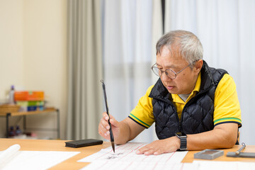 Asian old man practice Chinese calligraphy character at home