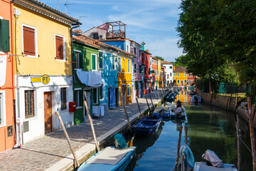 Multicolored colorful houses in Venice on the island of Burano. Narrow canal with motor boats along...