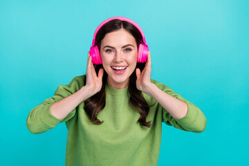 Portrait of positive funky lady beaming smile hands touch headphones isolated on teal color...