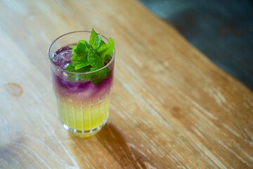 Sweet and Fresh Coctaiol Drink in Purple and Yellow Color isolated with Mint Leaf as Garnish On Top