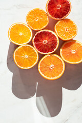 Fresh citrus fruits fool of vitamins: oranges and blood oranges (tarocco) on white background, sunlight, top view, summer vibes, natural  eco concept. Mediterranean diet
