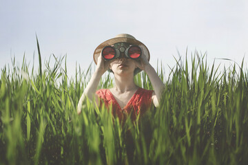 surreal woman with spyglass hidden in the grass, abstract concept